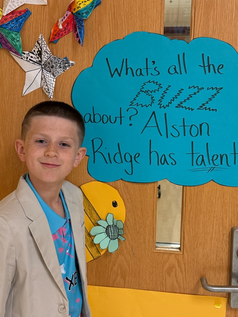 Holden in a tan blazer beside a classroom door sign that reads Alston Ridge has talent