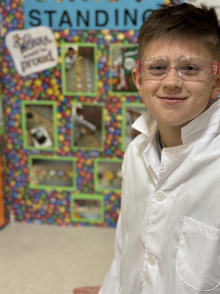 Holden in a white lab coat and safety glasses, smiling